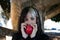 Punky girl with blonde and brunette hair holds a red apple in her hands and stares at it. The girl is a witch from the fairy tale