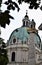Punta, of the great column, in front of the dome of the beautiful church of San Carlo Borromeo in Vienna, framed by leaves.