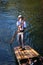 Punting. Punter in Edwardian clothes and white hat propelling a wooden flat-bottomed leisure boat in shallow water