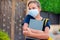 Pupil with face mask holding book staying outdoor. Back to school