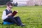 Pupil in glasses reads a book sitting on the grass