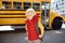 Pupil with schoolbag with yellow school bus on background