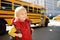 Pupil with schoolbag with yellow school bus on background