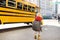 Pupil with schoolbag with yellow school bus on background