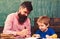 Pupil and teacher drawing in copybook. Father and son having fun together. Preschool education concept