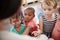 Pupils At Montessori School Looking At Book With Teacher