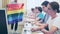 Pupils sitting in class and listening carefully to male teacher. He holding LGBT pride flag in hands and talking about