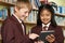 Pupils Wearing School Uniform Using Digital Tablet In Library