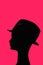 Puppet head silhouette profile wearing trilby straw hat, dark pink background