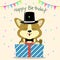 Puppy Corgi in a hat and a bow tie, sits and holds a box with a gift on the background of confetti and flags. Happy