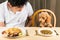 Puppy eyeing the plate of rice and meat on a teenagers plate and show no interest on her plate of kibbles