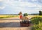 puppy red dog Corgi sits on two old suitcases on a rural road waiting for transport while traveling on a summer day