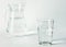 Pure clear water in a glass glass and glass jug stands on a white background