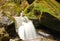 Pure fresh water waterfall running over mossy rocks in the forest