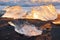 Pure Ice Shining on Black Volcanic Sand at Sunset. Icebergs from Glacier in Sun Rays. Clear Ice in Ocean Waves. Famous