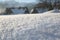 Pure untouched snow. Close-up. On the wavy surface, snowflakes sparkle in the sun..Village houses in the background