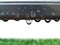 pure water drop on gray aluminum clothes line with blurry green grass lawn