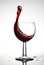 Pure wineglass with wave of brightly red wine on white background