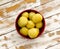 Purified boiled yellow potatoes in a red bowl on the old wooden table with the remnants of white paint closeup