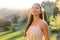 Purity and beauty concept. Portrait of beautiful girl breathing fresh air outdoor in nature with white dress and flower on ear