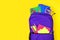 Purple backpack full of school supplies against a yellow background, top view with copy space