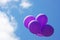 Purple balloons floating in blue sky