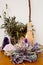 Purple beeswax candle, besom and dried herbs on altar with crystals