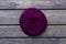 Purple beret hat on dark wood background.