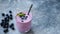 Purple blueberry acai smoothie in glass with drinking straw