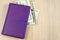 Purple business diary with dollar banknotes on light background