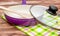 Purple ceramic frying pan with wooden shovel and glass lid on the kitchen`s towel