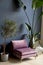 Purple chair against a dark blue wall.Plants in tubs.
