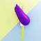 purple color eggplant impaled on stainless kitchen knives on yellow and blue pastel background. minimal food idea concept.