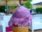 Purple color fruit flavored ice cream closeup in plain waffel cone.