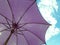 Purple colored parasol under vivid blue sky with white cloud