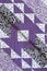 Purple coloured handmade patchwork bed quilt with various fabric geometric patterns