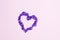 Purple confettis in the form of heart on pink background. Valentine`s Day decor
