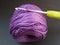 Purple crochet yarn and a crochet hook over black background.