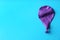 Purple deflated balloon on color background