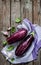 Purple eggplant (aubergine), garlic and basil leaves on vintage wooden table from above