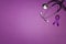 Purple epilepsy awareness ribbon with stethoscope and copy space on a purple background. World epilepsy day