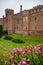 Purple flowers and Herstmonceux, East Sussex, England. Brick Herstmonceux castle in England East Sussex 15th century. View of a