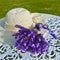 Purple French lavender beside a beige woven hat on a white wrought iron round table. Square photo image.