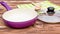 Purple frying pan with glass lid, kitchen wooden utensil and towel on the wooden table. Cooking meal