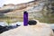 Purple gas lighter Cricket next to a black piece of coal in a desert area. A coal mine or quarry on a lake. Place of coal mining