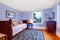 Purple guest bedroom with single wood bed and blue rug.