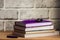 The purple handle rests on a purple diary, a stack of planings, a black clip, a brick background