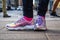 Purple holographic sneakers on a girl legs, with city in the background, selective focus