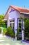 Purple house with white wooden windows under a red roof against a blue sky.