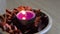 Purple light candle in a wooden bowl filled with potpourri.